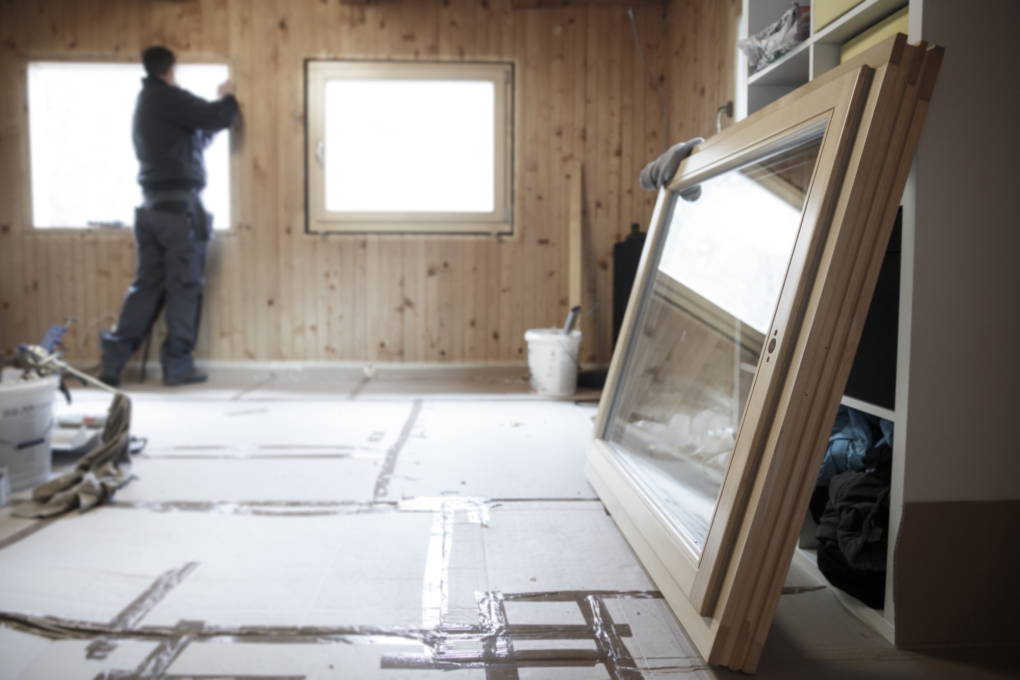 Worker in the background installing new three pane wooden windows.