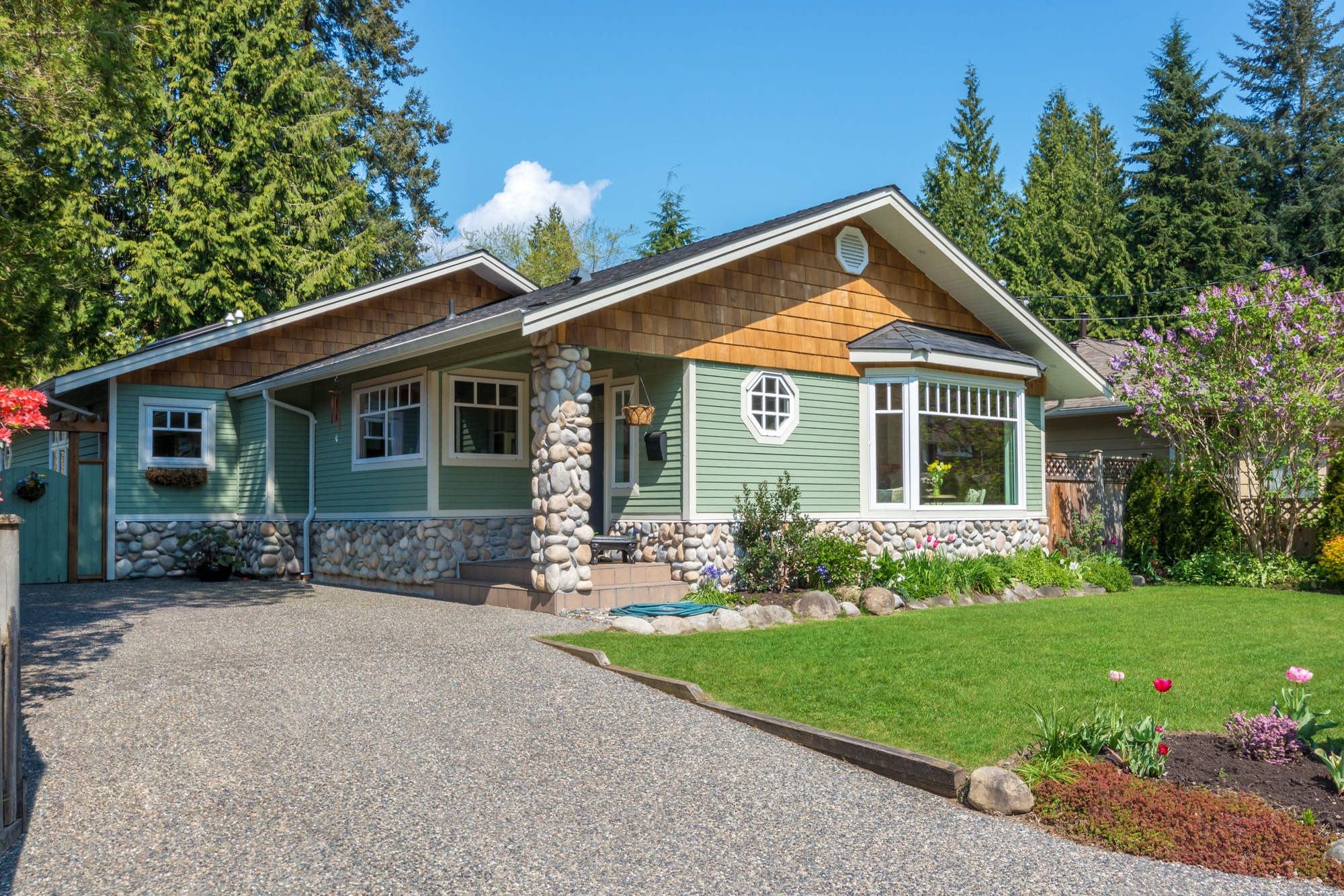 Cozy green house with beautiful landscaping on a sunny day.